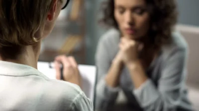 Young depressed woman talking to lady psychologist during session, mental health